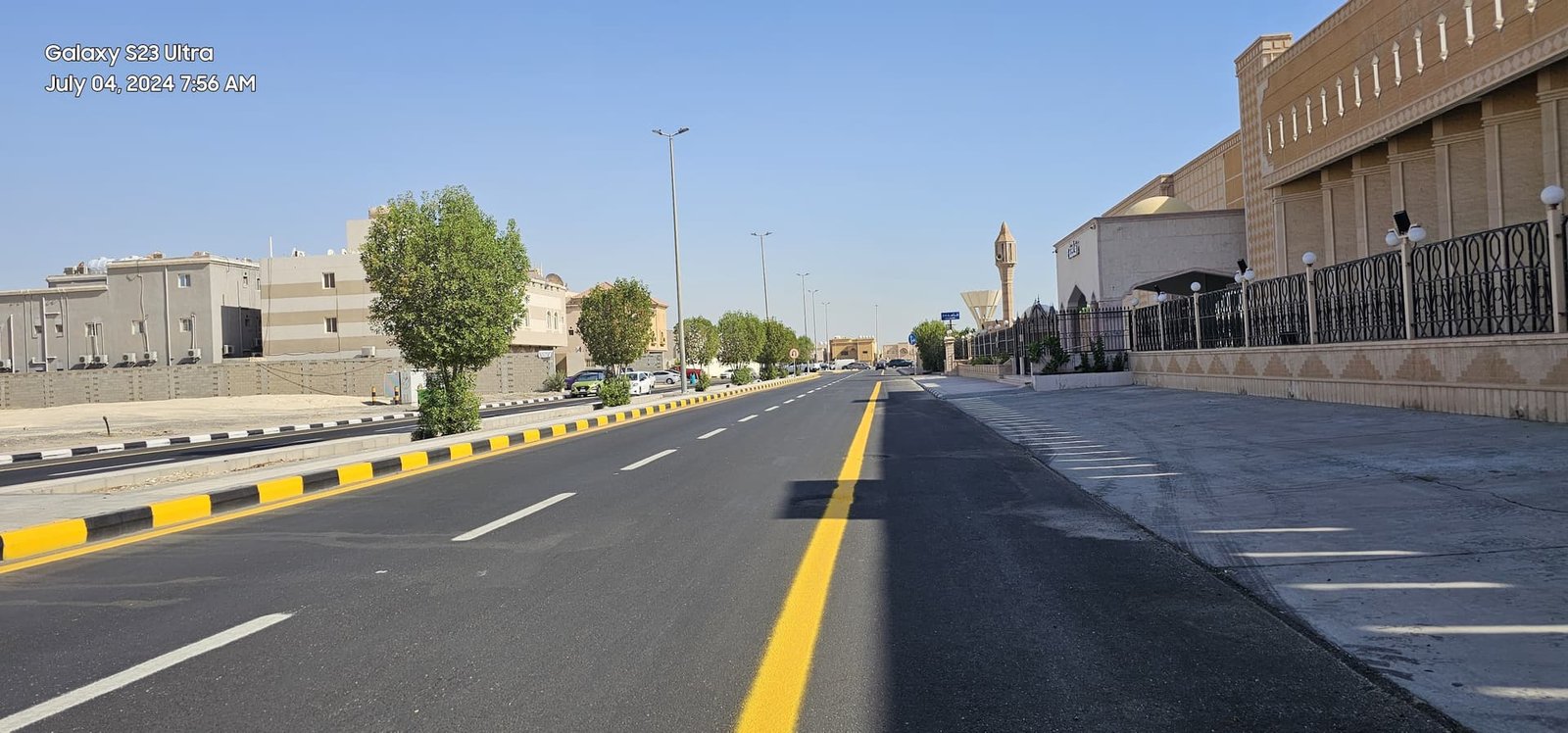 Completed street with lighting poles near a mosque